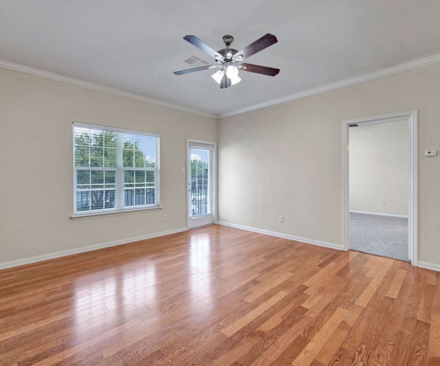 Riviera Apartments in Waco, TX with large living room, ceiling fan, large windows and natural light, and hardwood-style vinyl plank flooring
