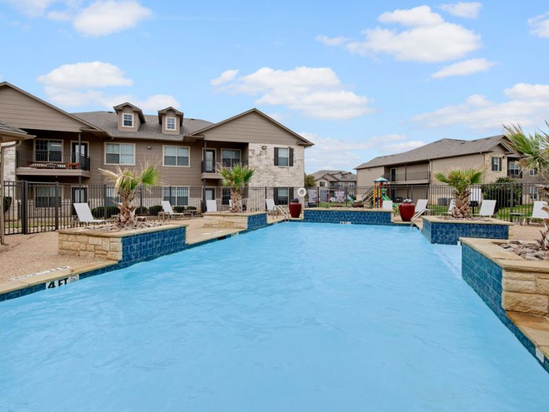 Riviera Apartments in Waco, TX with the community swimming pool, sun deck, and clubhouse in the background