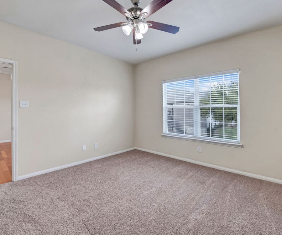 Riviera Apartments in Waco, TX with spacious, carpeted bedroom with ceiling fan and large windows