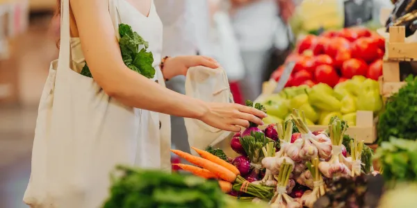 Woman putting locally grown vegetables into her bag at the farmers market